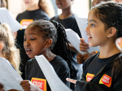 Young Stagecoach students singing from song sheets in class