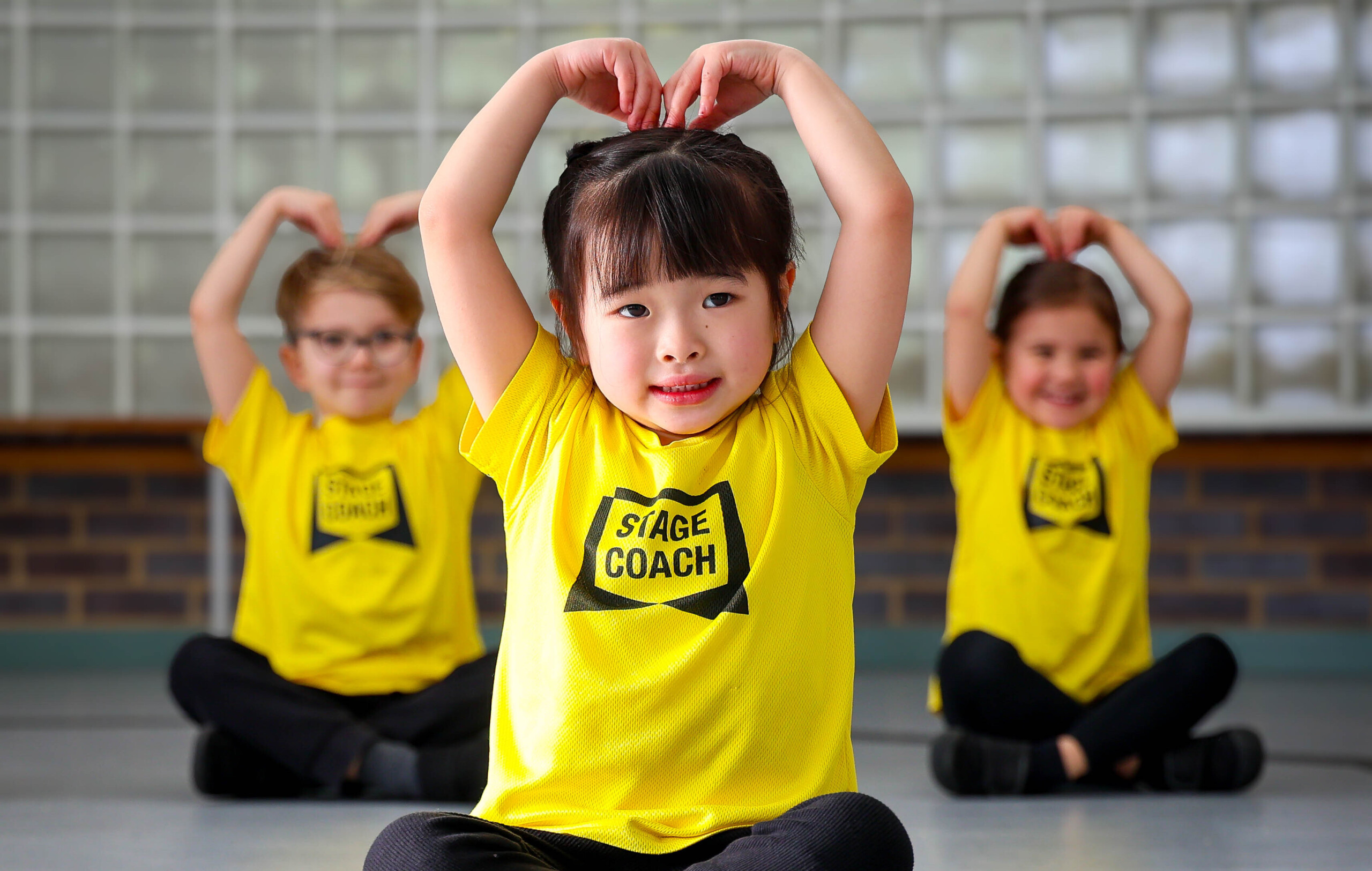 Early Stages children in yellow T-shirts making heart shapes with their arms