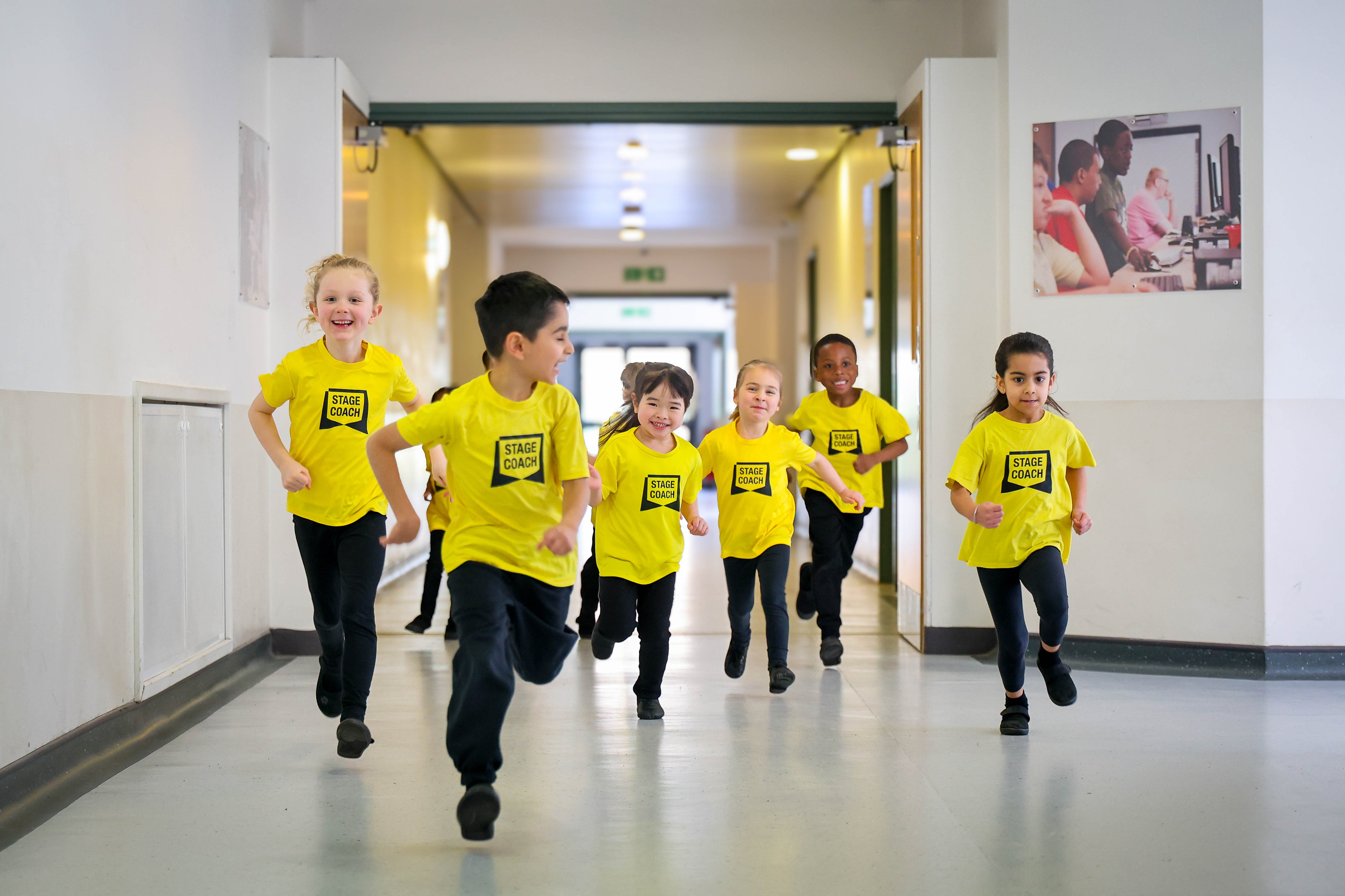 Early Stages children in yellow Stagecoach T-shirts running down a hallway