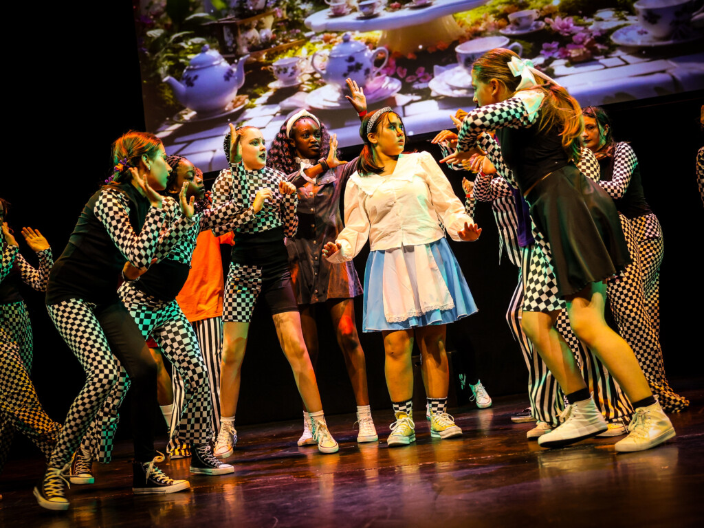Stagecoach students in costume dancing on stage in an Alice in Wonderland tea party scene