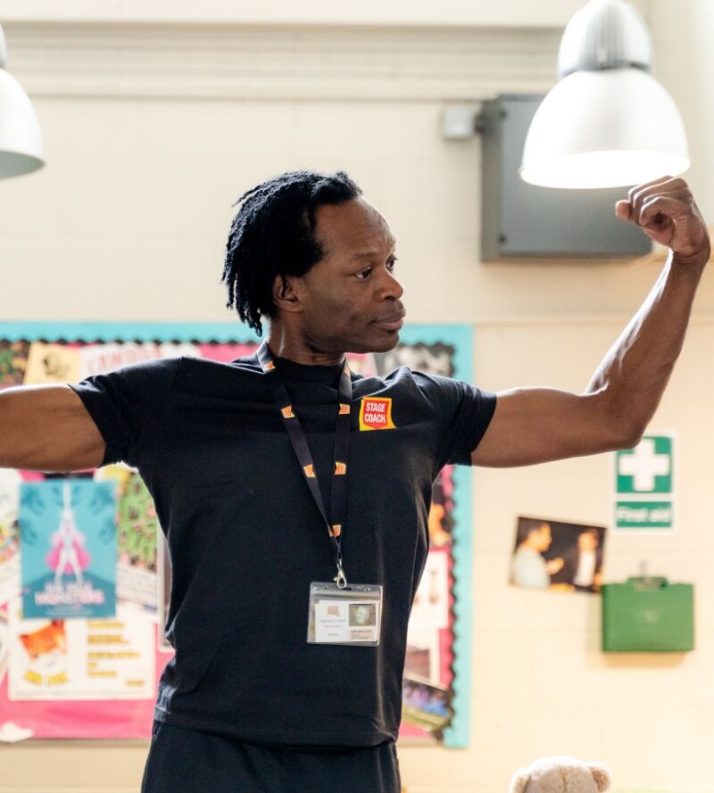 Stagecoach teacher leading children in a performing arts classroom activity.